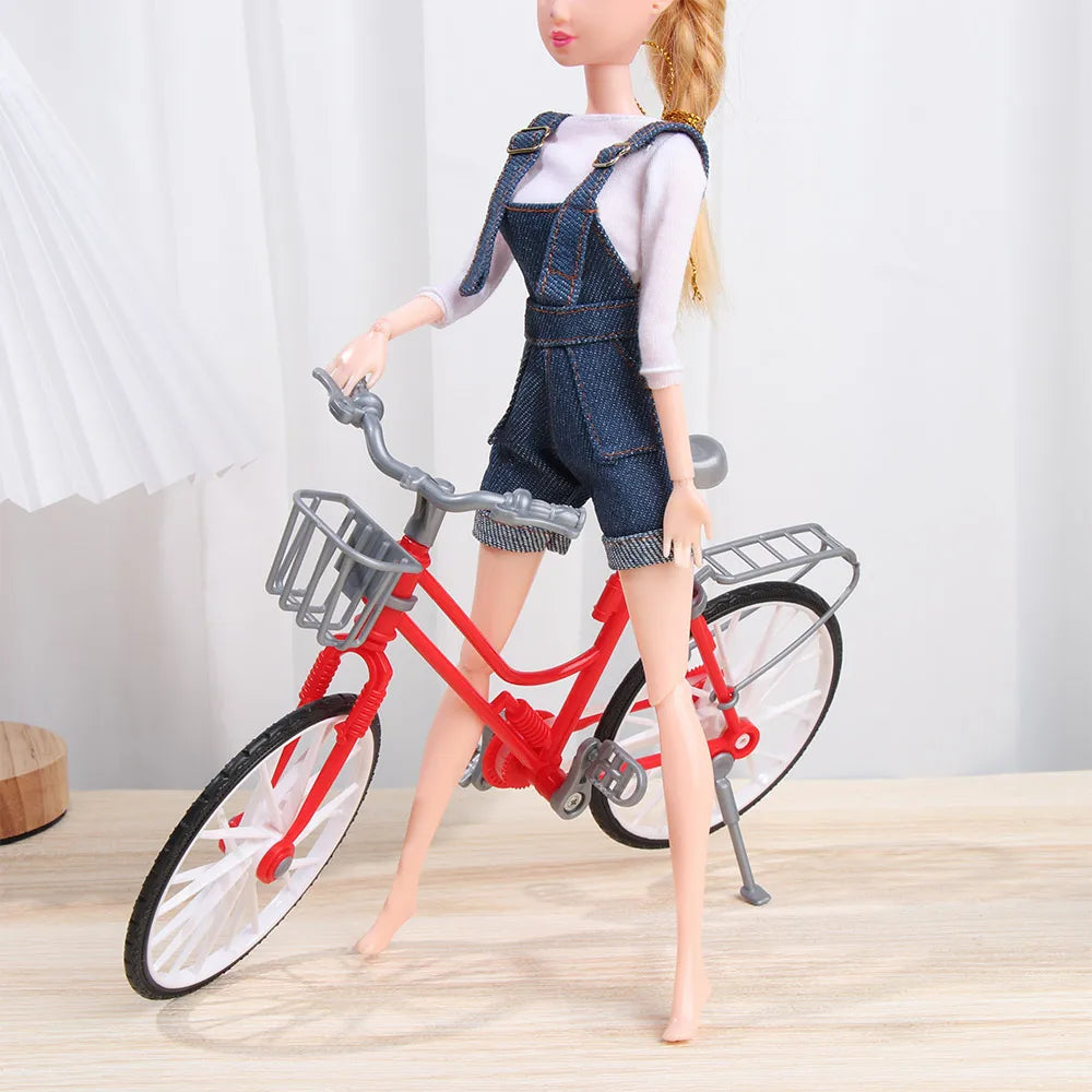 A mini doll wearing denim overalls and a white t-shirt standing next to a red bicycle.