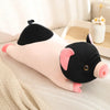 A pink and black plush pig stuffed animal lying on a light surface.