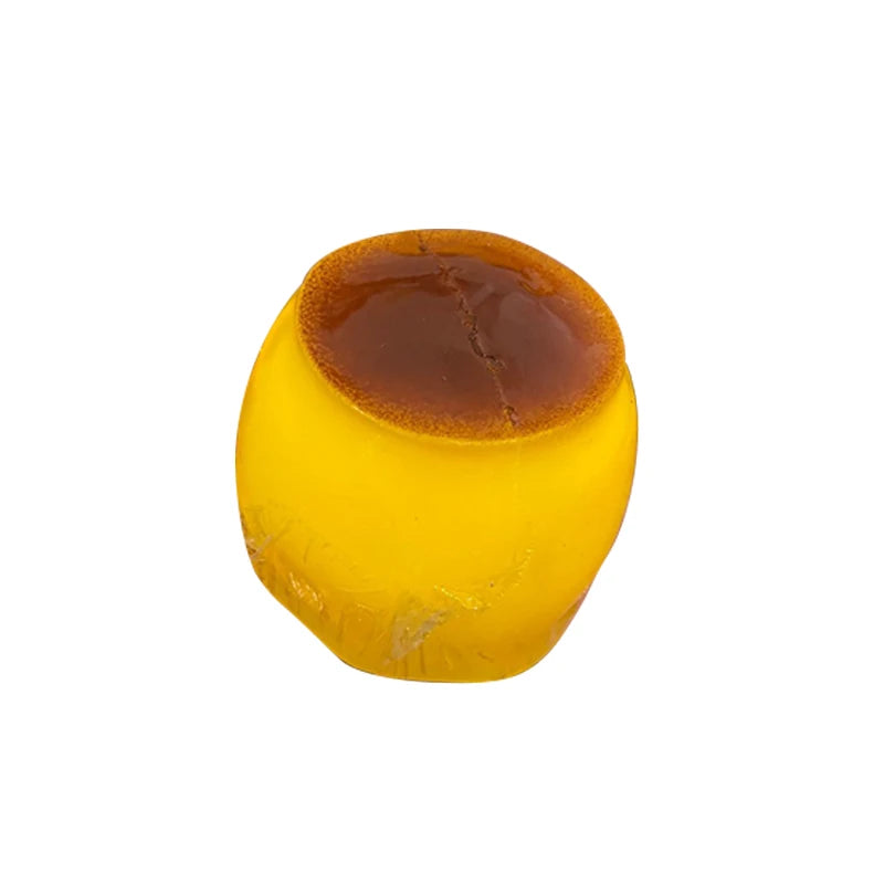 A round, yellow caramel pudding squishy stress relief ball with a darker brown top.