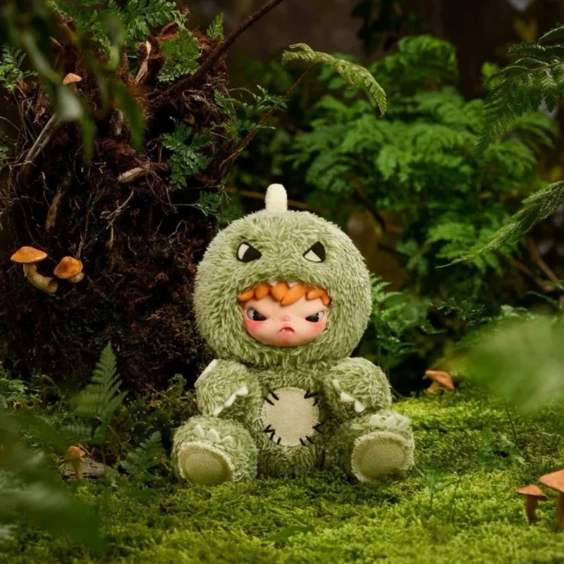 A soft green plush doll resembling a creature with large eyes and horns sitting in a lush, green outdoor setting.