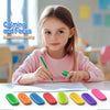 Une jeune fille écrit avec un crayon vert sur du papier, entourée de diverses bandes anti-stress en silicone colorées.