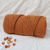 A tightly coiled bundle of natural brown cotton macrame rope for crafts and decor.