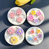 A set of silicone molds shaped like various daisy flowers in pink, purple, and yellow for cake decorating.