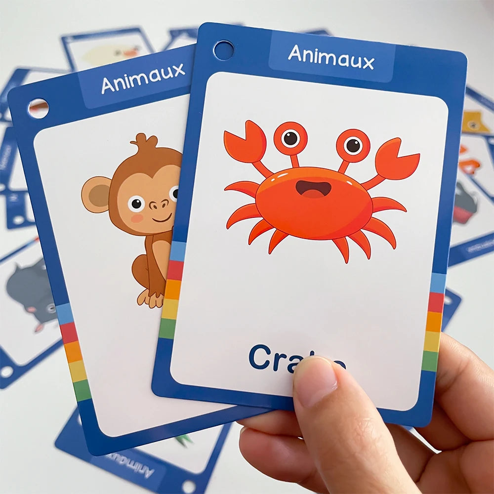 A hand holds a blue flash card titled Animaux featuring an orange crab illustration.