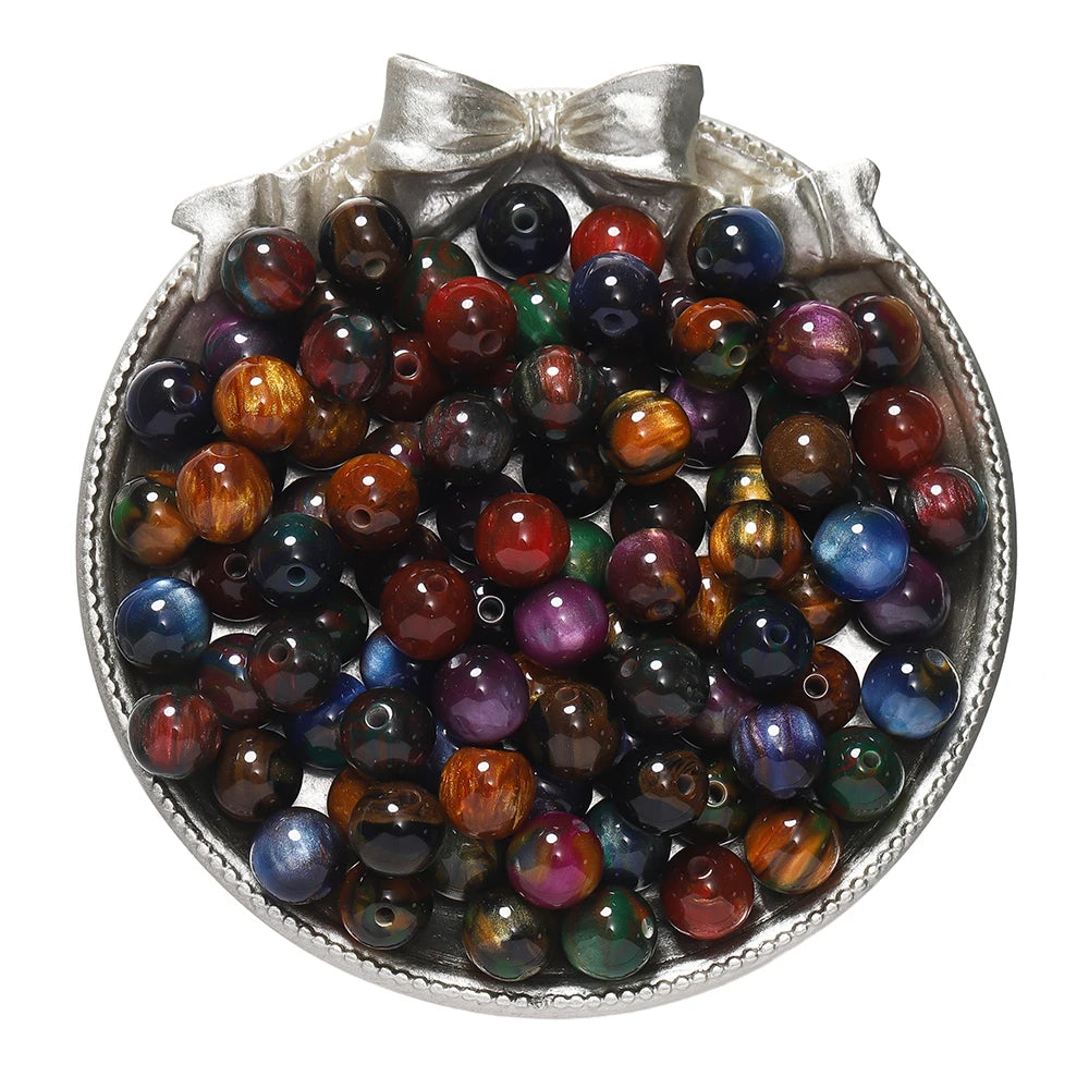 A silver dish filled with round, colorful glitter cat eye resin beads for jewelry making