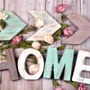 Wooden letters spelling HOME made from light and dark wood with pink floral accents