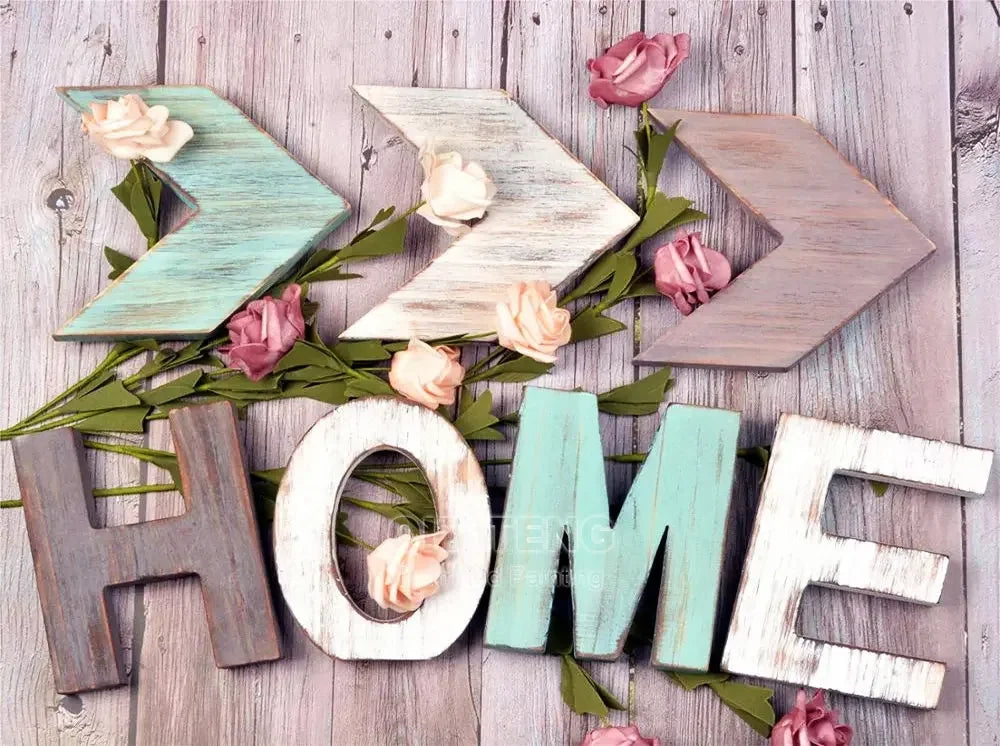Wooden letters spelling HOME made from light and dark wood with pink floral accents