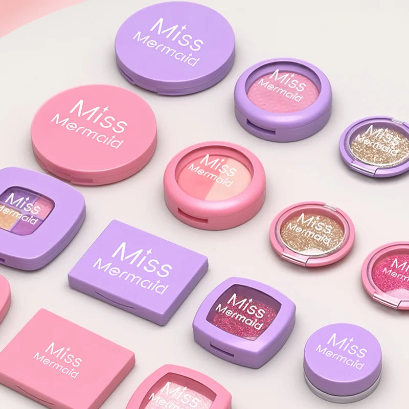 A collection of Miss Mermaid cosmetic products including lip and eye shades in various pink and purple packaging.