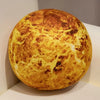 A round, golden-yellow plush toy resembling a celestial body, displayed on a white pedestal.