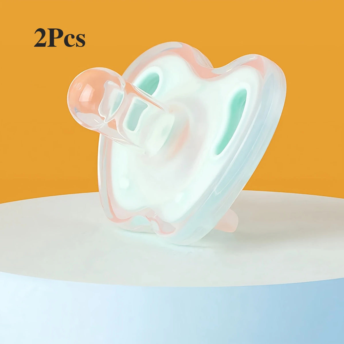 Two soft silicone baby pacifiers in pink and mint green resting on a white surface.