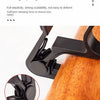 A close-up view of a black guitar capo clamp mechanism being applied to the wooden body of a guitar.