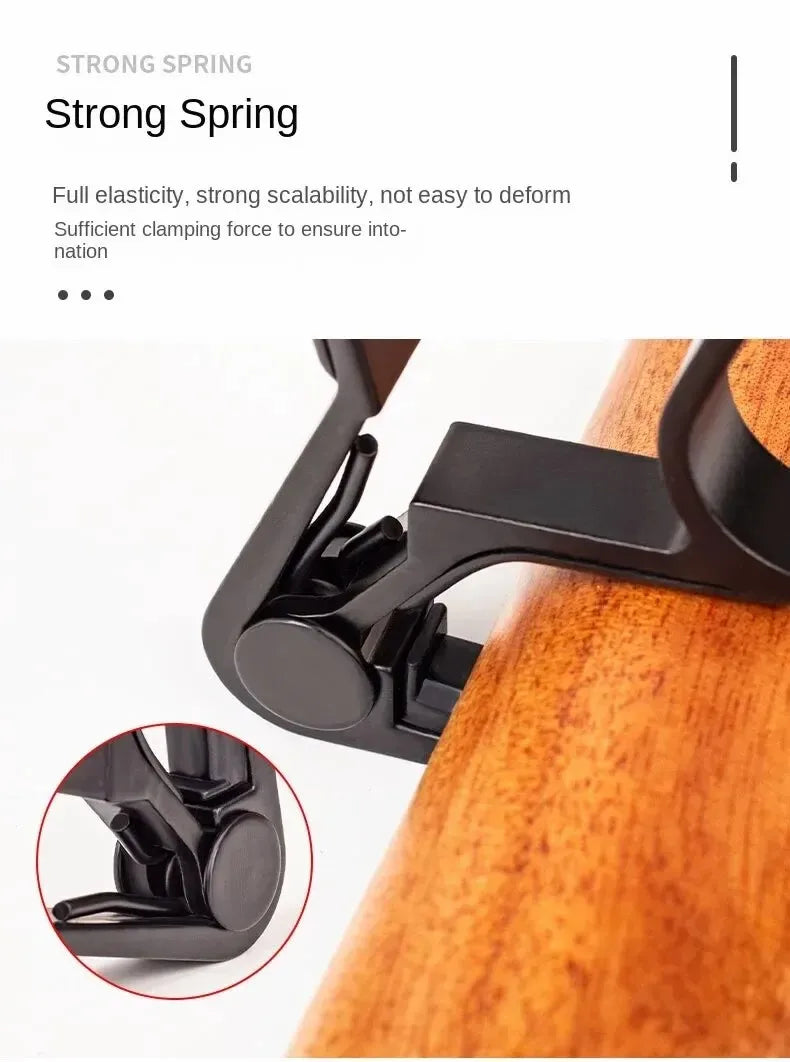 A close-up view of a black guitar capo clamp mechanism being applied to the wooden body of a guitar.