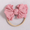 Pink knitted fabric bow headband with a light beige elastic band