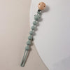 A silicone pacifier clip featuring a wooden bear paw top and a string of small, light green silicone beads.