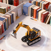 A yellow mini RC excavator is shown rotating on a white surface amidst a background of books and building blocks.