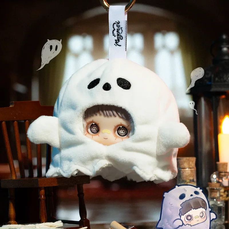 A white ghost-shaped vinyl plush blind box with black eyes and dark hair is displayed in a dimly lit setting.