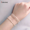 A hand is wearing a delicate white pearl beaded bracelet on its wrist.