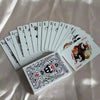 A stack of black and white poker cards is displayed on a satin fabric background.