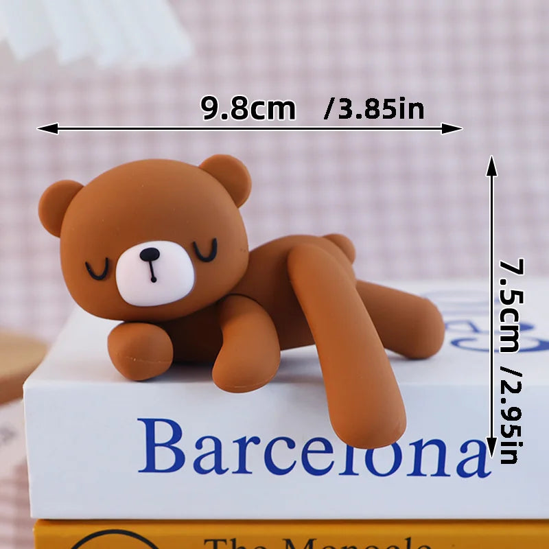 A small, brown 3D bear cake topper with a white nose and ears, shown next to a book.