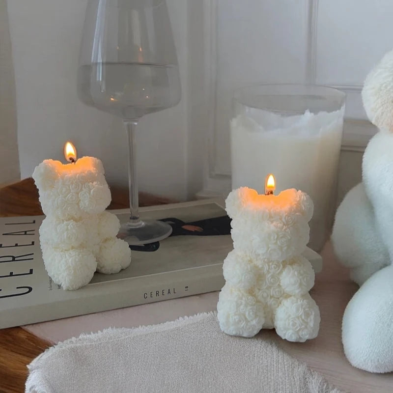A white silicone mold shaped like a bear is shown next to a lit candle and a glass of milk.