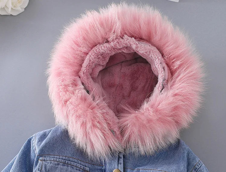 A denim jacket with a fluffy pink faux fur collar is displayed against a gray background.