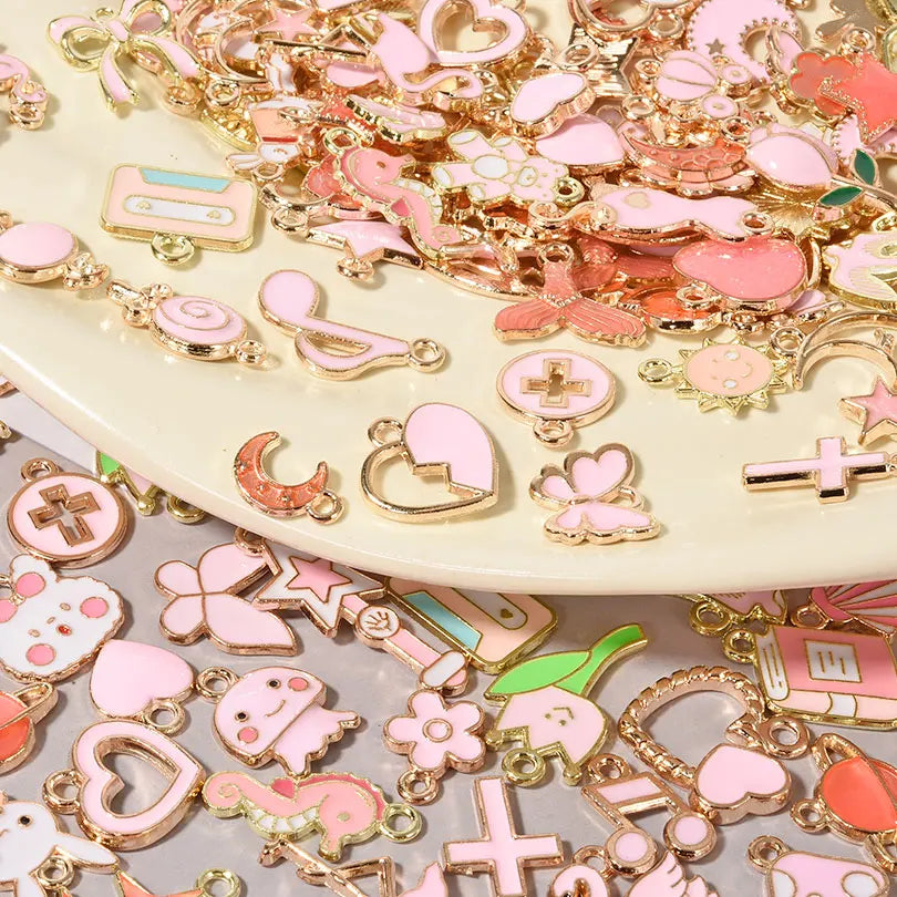 Assorted metal pendants and charms in pink, gold, and green for jewelry making