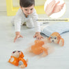 Un jouet singe électrique orange roule sur un parquet en bois clair avec un enfant à proximité.