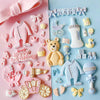 A collection of pink and white silicone baby-themed cake molds including a stroller, bottle, pacifier, and various accessorie