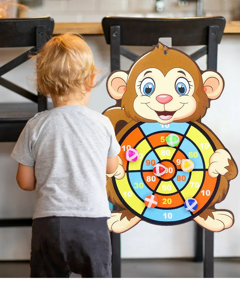 A young child is looking at a cartoon monkey dart board game with colored targets.