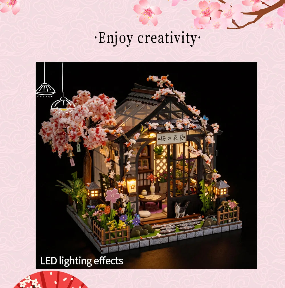 A detailed miniature Japanese tea house model featuring pink blossoms and LED lighting effects.