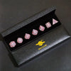 A set of pink resin polyhedral dice displayed in a black box with a gold planet logo.