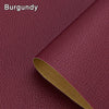 A close-up of a burgundy leather material with a brown edge, showing the texture and thickness of a self-adhesive repair patc