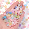 A hand holds a pile of colorful transparent star acrylic beads for jewelry making