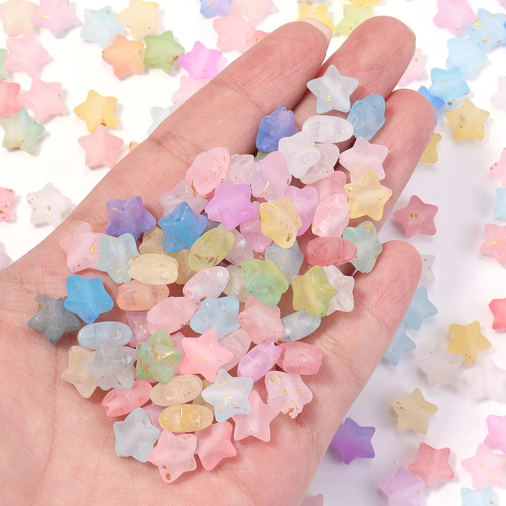A hand holds a pile of colorful transparent star acrylic beads for jewelry making
