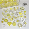 A collection of mixed yellow and clear acrylic bow and flower beads for jewelry making.