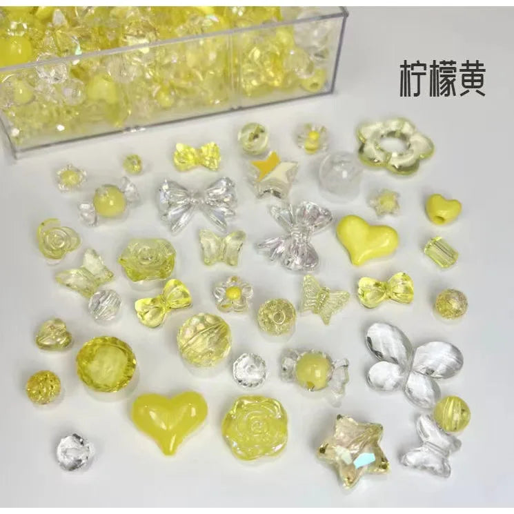 A collection of mixed yellow and clear acrylic bow and flower beads for jewelry making.