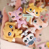 A hand holds a set of miniature pet animal figures including a pink cat, a yellow fox, and several other small animals.