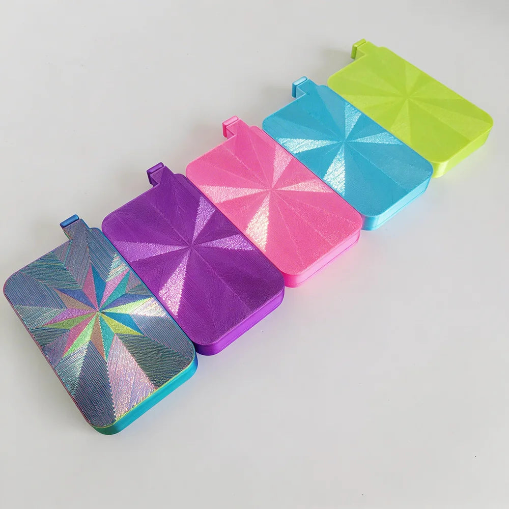 A collection of six iridescent diamond painting trays in various bright colors, arranged diagonally on a white surface.