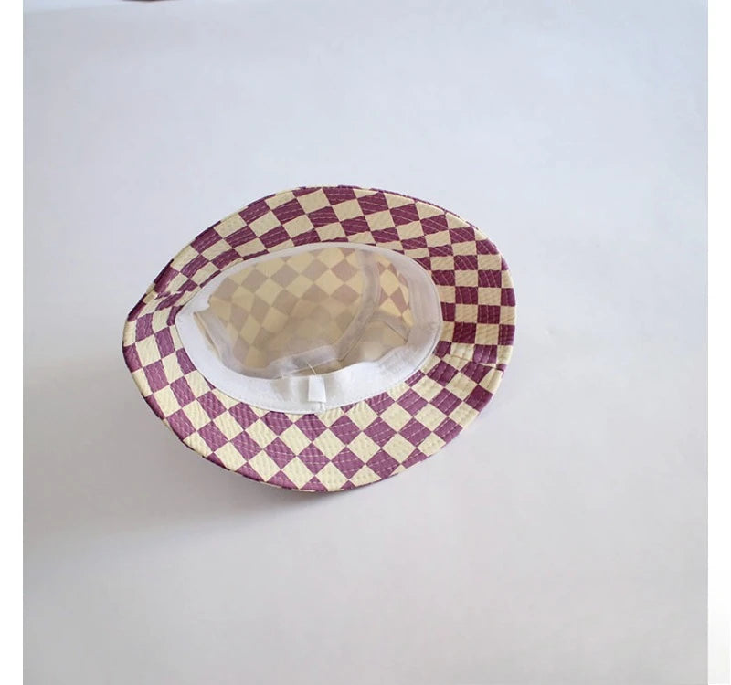 A round bucket hat with a checkered pattern in purple and cream fabric.