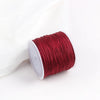 A roll of deep red macrame cord for jewelry making and crafts.