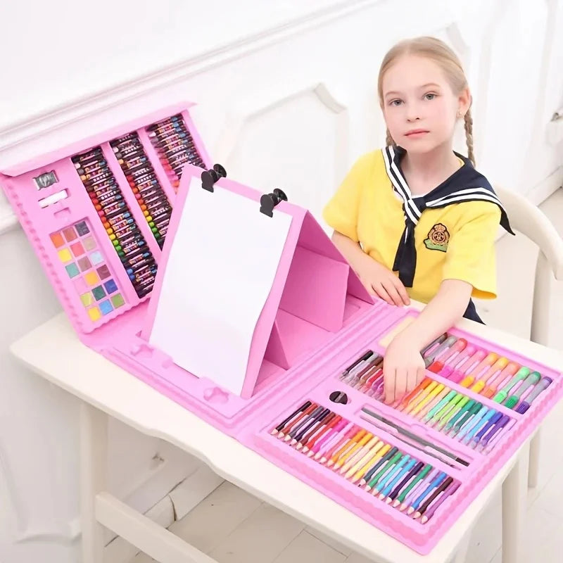 A young girl is holding a pink art set with an easel and various colored art supplies on a white table.
