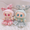 A pair of cute plush dolls dressed in pink and green plaid outfits with frilly sleeves and princess shoes
