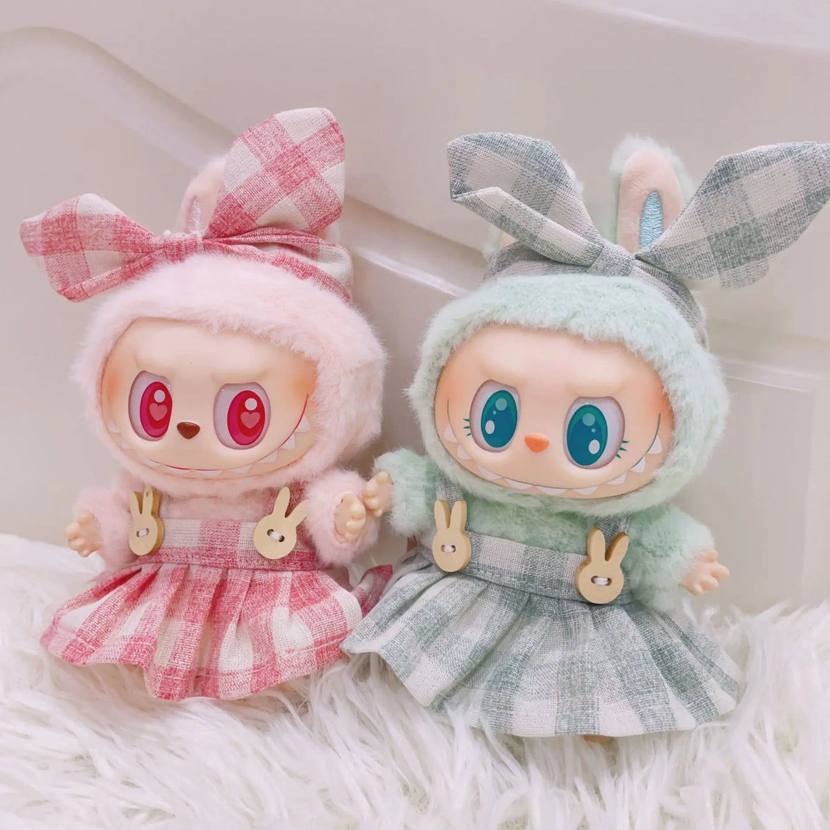 A pair of cute plush dolls dressed in pink and green plaid outfits with frilly sleeves and princess shoes