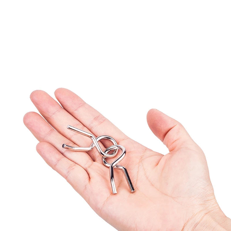 A hand holds a silver metal wire puzzle set consisting of interconnected loops and ends.