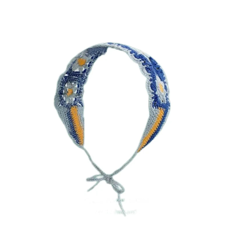 A handmade strawberry crochet headband featuring blue and orange yarn with a wide elastic band.