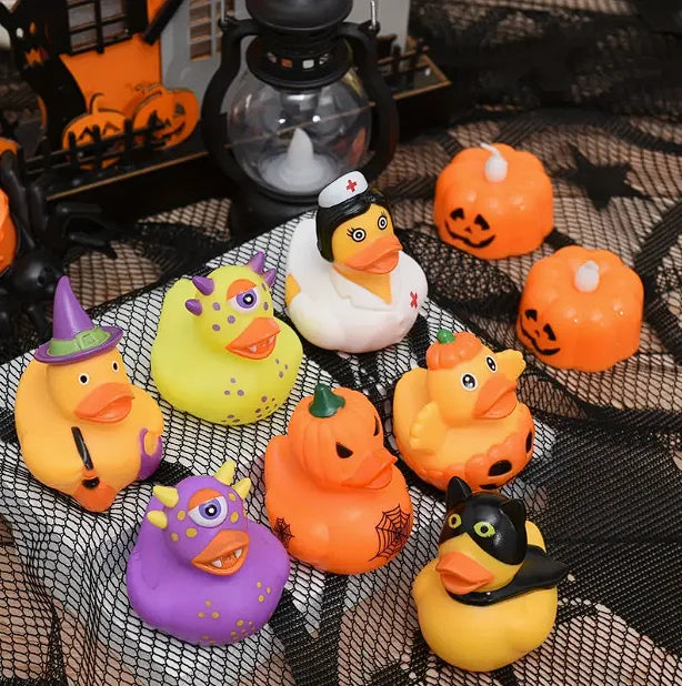 A collection of orange and yellow Halloween pumpkin rubber ducks are displayed on a black mesh surface.