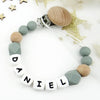 A beaded pacifier clip featuring wooden and silicone beads spelling out the name Daniel
