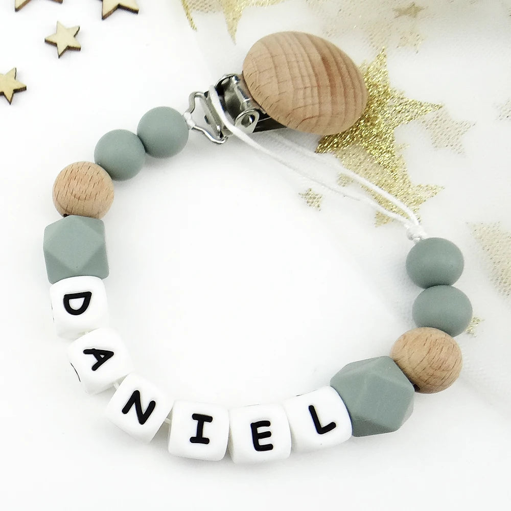 A beaded pacifier clip featuring wooden and silicone beads spelling out the name Daniel