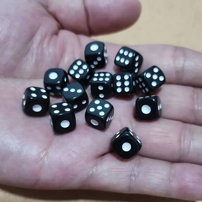 A hand holds a pile of ten black and white six-sided dice on a light surface.