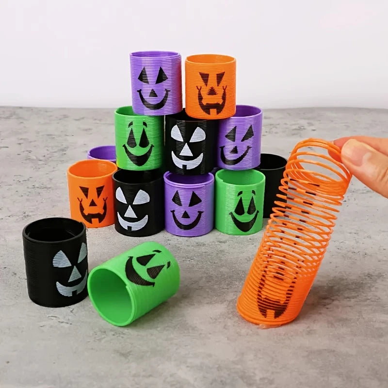 A stack of colorful Halloween pumpkin coil spring toys in purple, orange, and green, with one toy lying horizontally.